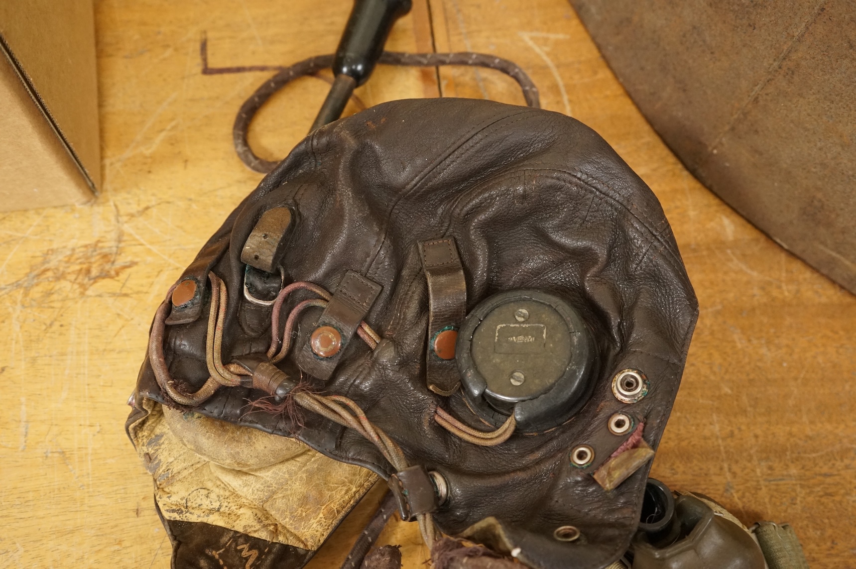 A WWII RAF Air Ministry aviator’s leather head-gear, with built-in padded headphones, oxygen mask with microphone and other electrics incorporated into it, marked with a crown and ‘AM 10A/13466’ to one earpiece, together